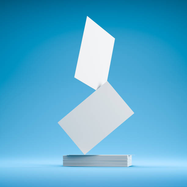 istock Business Card mockup. Several blank business cards on a stack on a blue seamless background. Two business cards balancing on top. 1331086970