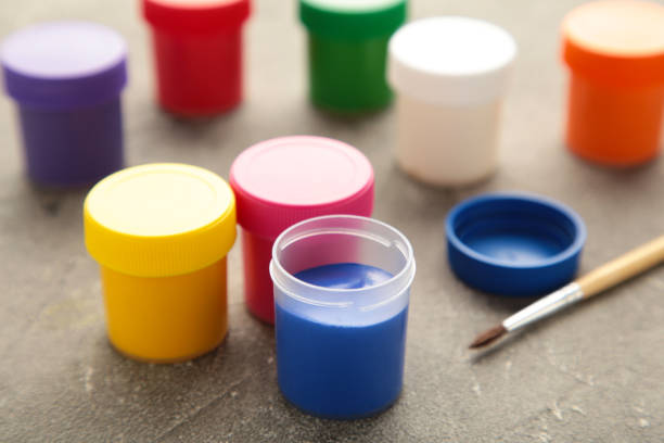 istock Multicolored jars of gouache and a brush on a grey background. Creative kit. 1331087822