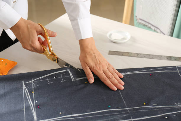 istock Seamstress cutting fabric following chalked sewing pattern at table in workshop, closeup 1331089081