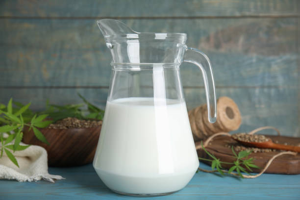 istock Pitcher of hemp milk on light blue wooden background 1331089242