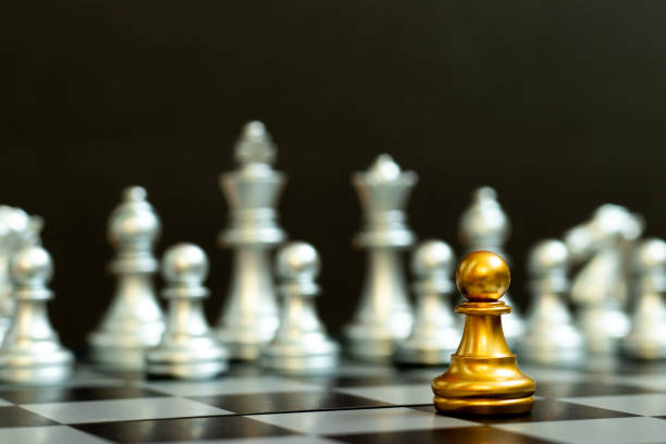 istock Gold pawn in chess game face with the another silver team on black background (Concept for company strategy, business victory or decision) 1331089243