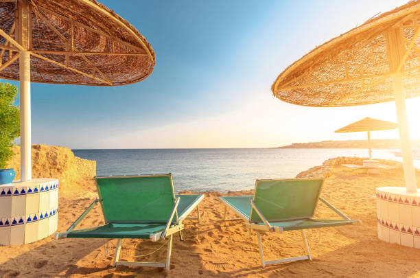 istock Umbrellas and two empty deckchairs on the shore sand beach 1331090669