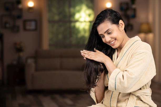 shot of a young women in bathrobe doing hair massage at home young women, refreshing, hair care, oil, massage, India, Indian ethnicity, hair care stock pictures, royalty-free photos & images