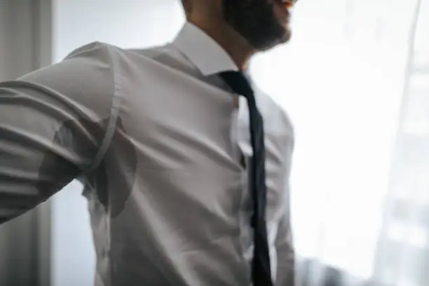 Photo of Man with hyperhidrosis sweating under armpit in shirt