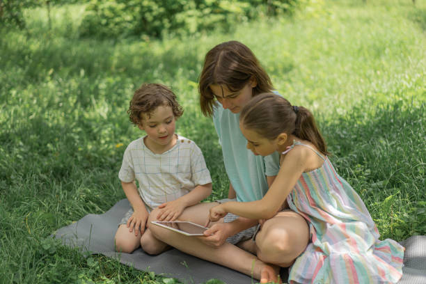 istock Children with a tablet outdoors. Children play games on the tablet. Technology concept 1331092894