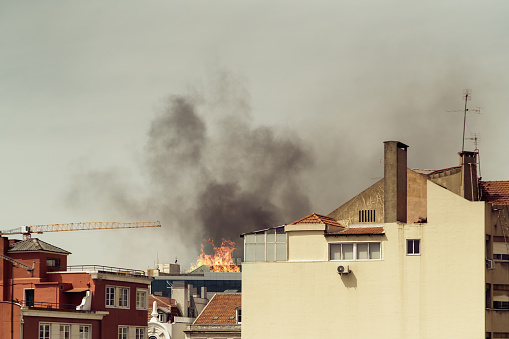 An emergency situation: a fire in a residential area of a European city: clouds of black smoke rising behind the facades of dwelling houses of a district