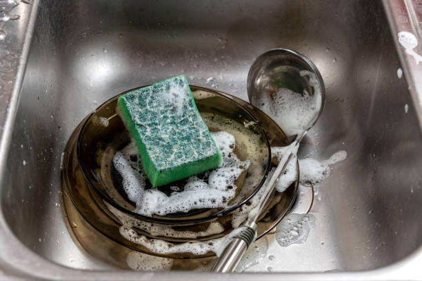 istock A stack of plates and a ladle with a sponge for washing in soapy foam in the kitchen sink. 1331095708