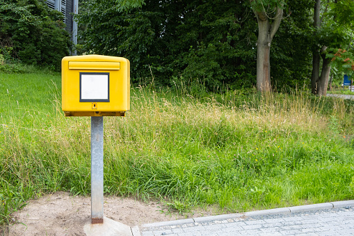 un buzón de correos amarillo se encuentra en las afueras de la carretera, en algún lugar de Europa photo