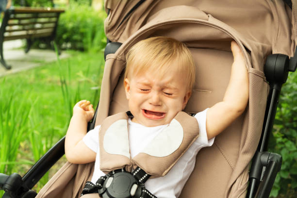 Little caucasian sad baby girl, crying sitting at carriage on background of green grass in summer park.Frustrated kid oudoors Little caucasian sad baby girl, crying sitting at carriage on background of green grass in summer park.Frustrated kid oudoors. outing tantarum in babies stock pictures, royalty-free photos & images