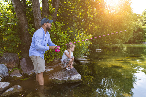 Father and cute little danish girl with blond hair fishing for perch at a lake in Denmark