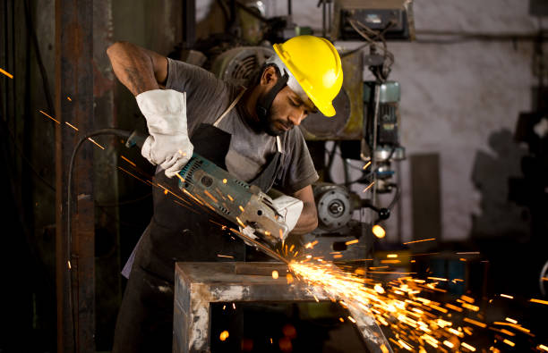 Mechanic using circular saw grinder tool at factory Mechanic using circular saw grinder tool in protective workwear at factory worker with grinding machine power tool in factory stock pictures, royalty-free photos & images