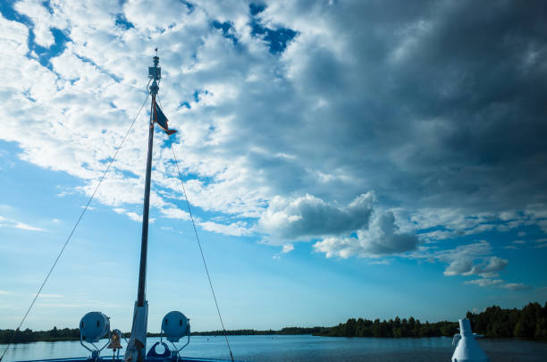 The bow of a ship sailing along the river. Ahead is the horizon and white clouds in the sky. Travel along the Volga.