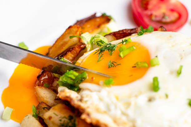 istock Fried potatoes with egg with liquid flowing yolk, herbs and tomatoes on a white plate. 1331102062