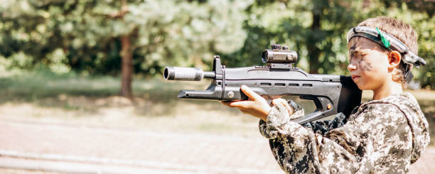 istock Boy looking into the optical sight a weapon. Children playing laser tag shooting game in outdoor. War simulation game. Banner 1331102177