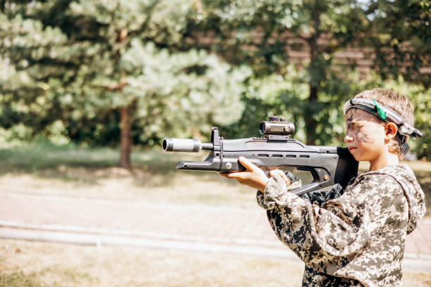 Boy looking into the optical sight a weapon. Children playing laser tag shooting game in outdoor. War simulation game