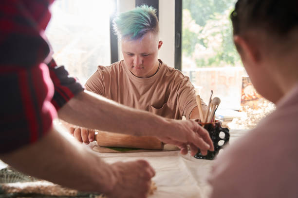 istock Man with colored hair rolling out fresh leaf over the clay to make an impression 1331102659