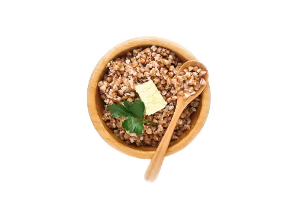 Photo of Buckwheat porridge in bamboo bowl with parsley leaf and butter isolated in white background. Gluten free ancient grain for healthy diet. Top view. Copy space.