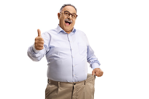 Smiled senior adult businessman standing with crossed hands in a modern building hallway