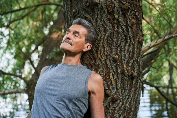 istock Man keeping eyes closed and relaxing in the forest while laying at the trunk 1331110761