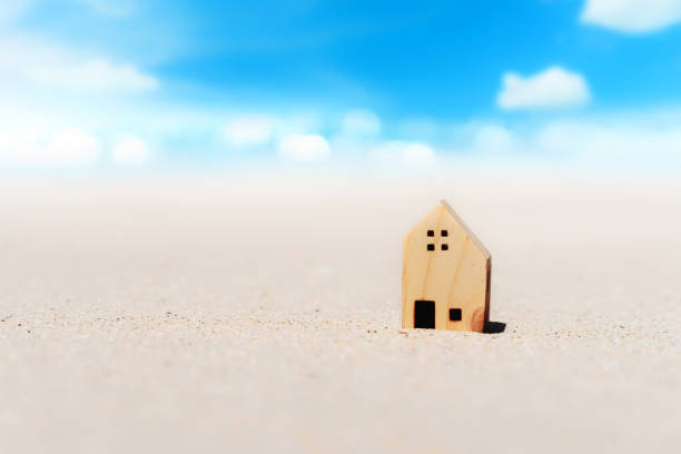 istock Small home model on sand beach with blue sky and white clouds background. 1331111703
