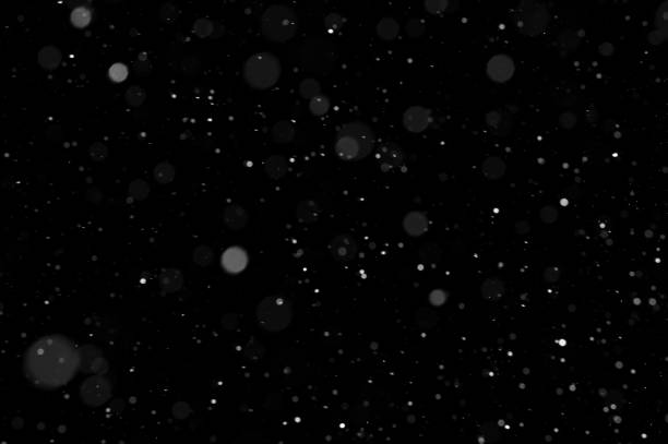 istock Bokeh of white snow on a black background. Snowfall - design element. 1331112834
