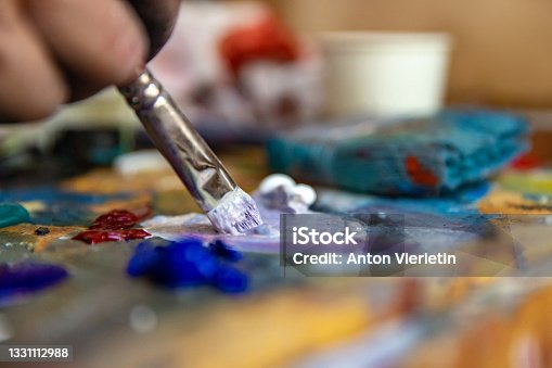 istock Closeup of hand mixing paint on palette at workshop 1331112988