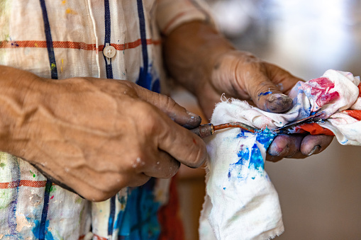 Closeup of hand mixing paint on palette at workshop. Concept of professions and unusual people. Hands closeup