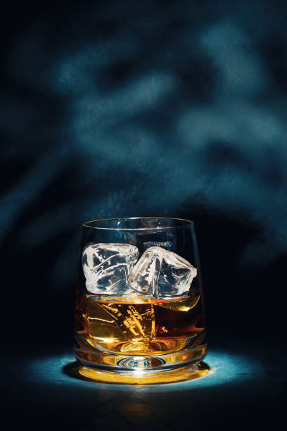 At the end of a hard day Late night glass of malt whisky with ice on a slate table with moonlight through the window on the wall behind. bourbon whiskey photos stock pictures, royalty-free photos & images