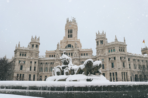 Madrid city center with the Cibeles monument and the city hall palace covered in snow - Postcard from Spain in winter