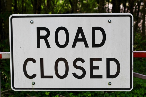 A close view of the black and white road closed sign.