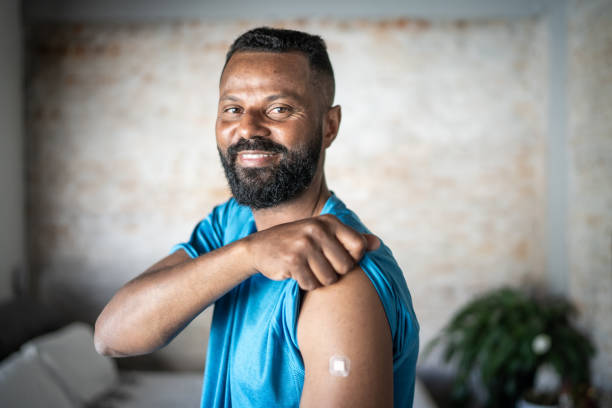 Happy mature man showing arm after vaccination Happy mature man showing arm after vaccination rolled up sleeves stock pictures, royalty-free photos & images