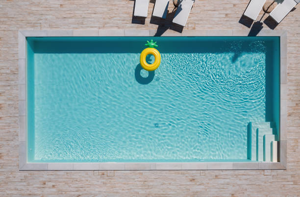 piscine bleue rectangulaire vide avec chaises longues et parasols et grand tube flottant gonflable d’ananas jaune. louez un bien immobilier ou détendez-vous des vacances d’été dans des stations de luxe concept. - inflatable ring photos photos et images de collection