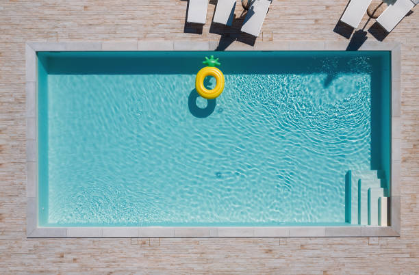 일광욕용 침대와 우산, 큰 팽창식 옐로우 파인애플 플로팅 튜브가 있는 빈 직사각형 블루 수영장. 부동산을 임대하거나 고급 리조트 개념으로 여름 휴가를 진정. - floatation device 뉴스 사진 이미지