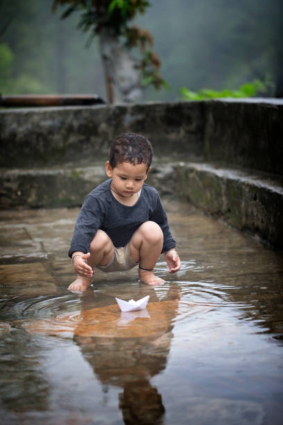 istock Boy sailing a paper boat 1331129413