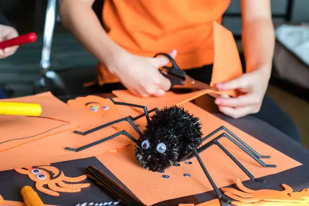 Photo of Halloween kids craft preparations. Little child doing autumn crafts at home.