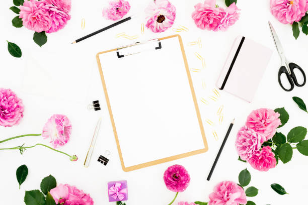 istock Flat lay work place with clipboard, pink flowers and accessories on white background. Flat lay, top view. 1331130600