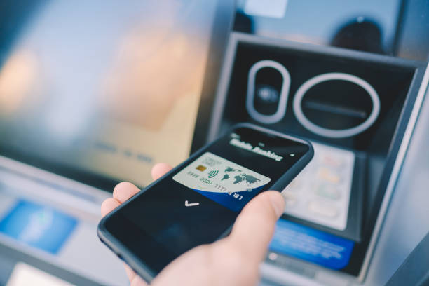 hombre en el cajero automático retirando dinero con smartphone - tecnología de finanzas fotografías e imágenes de stock