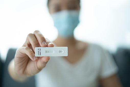 Asian young woman with hygiene protective face mask using SARS 2019-nCoV COVID-19 coronavirus antigen rapid test kit - ag test kit at home. COVID-19 antigen rapid test.