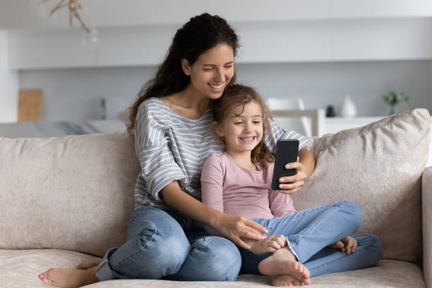 istock Smiling Latin mom and small daughter talk on cellphone 1331134320