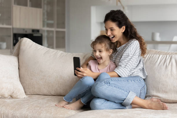 istock Excited Latino mom and daughter triumph using cellphone 1331134328