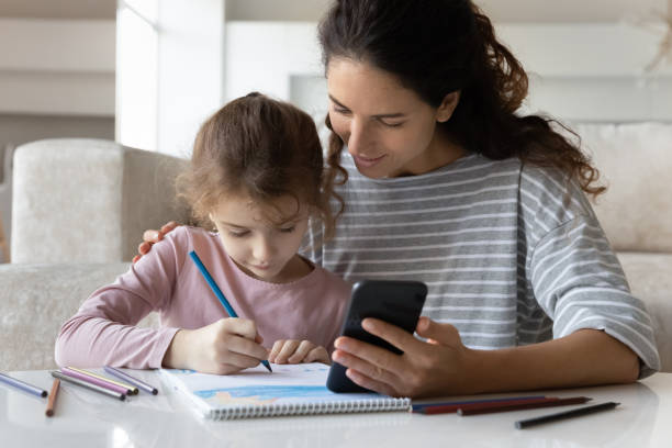 istock Loving Latin mom and daughter drawing using cell 1331134336
