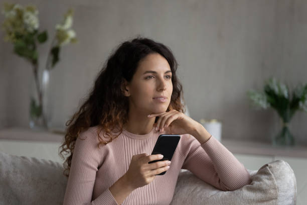 istock Dreamy young Latin woman use cellphone at home 1331134399