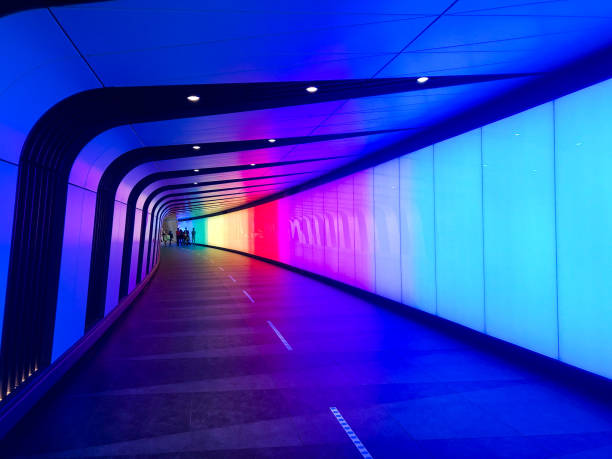 Colourful pedestrian tunnel at the train station in London. You can see shapes of people far away at the other end of the tunnel.