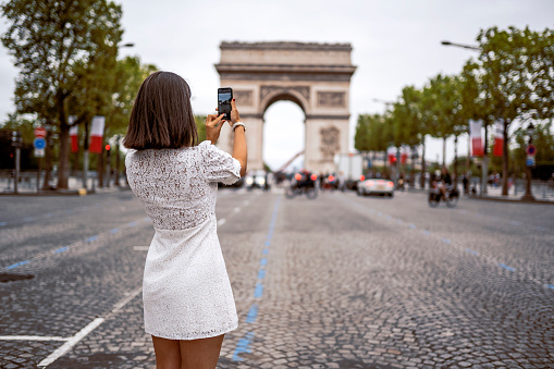 Shot of a young woman taking photographs with a smartphone while touring the city of Paris