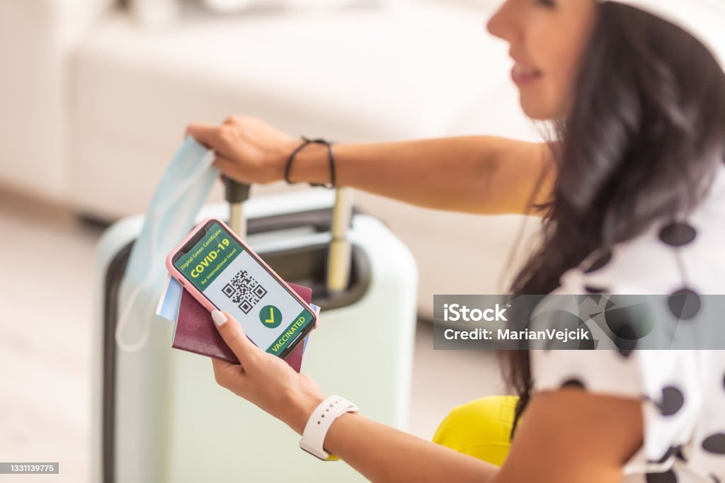 Travelling documents like passport, fly ticket and covid-19 pass with QR code and face mask in hands of traveller. Passing - Sport Stock Photo