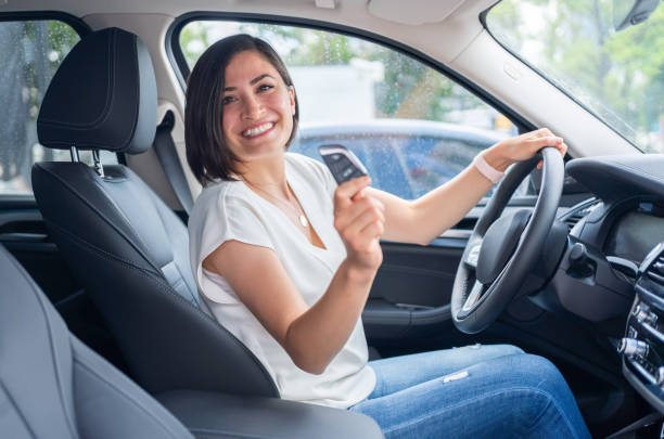 donna in possesso della chiave dell'auto della sua nuova auto elettrica - car insurance women driving foto e immagini stock