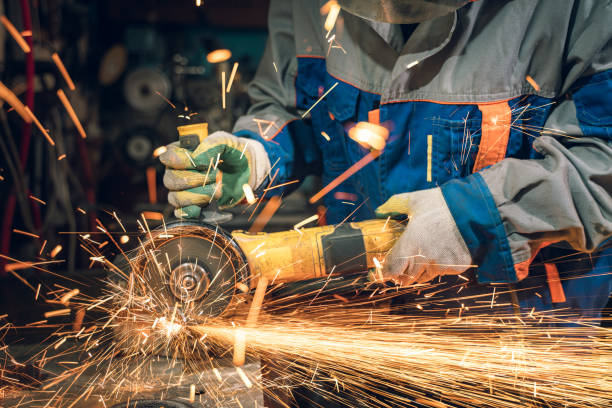 istock Locksmith in special clothes and goggles works in production. Metal processing with angle grinder. Sparks in metalworking 1331148424