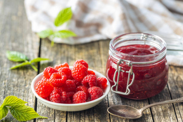 istock Red rasberries jam in jar and ripe raspberries. 1331149066