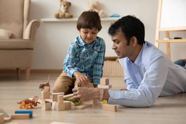 liebevoller indischer vater und kleiner sohn, die zusammen mit spielzeug spielen - child playroom parent indoors stock-fotos und bilder