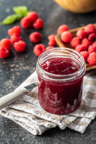 istock Red rasberries jam in jar and ripe raspberries. 1331149340